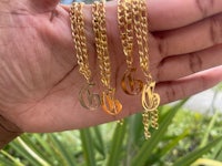 three gold chain necklaces with initials on them